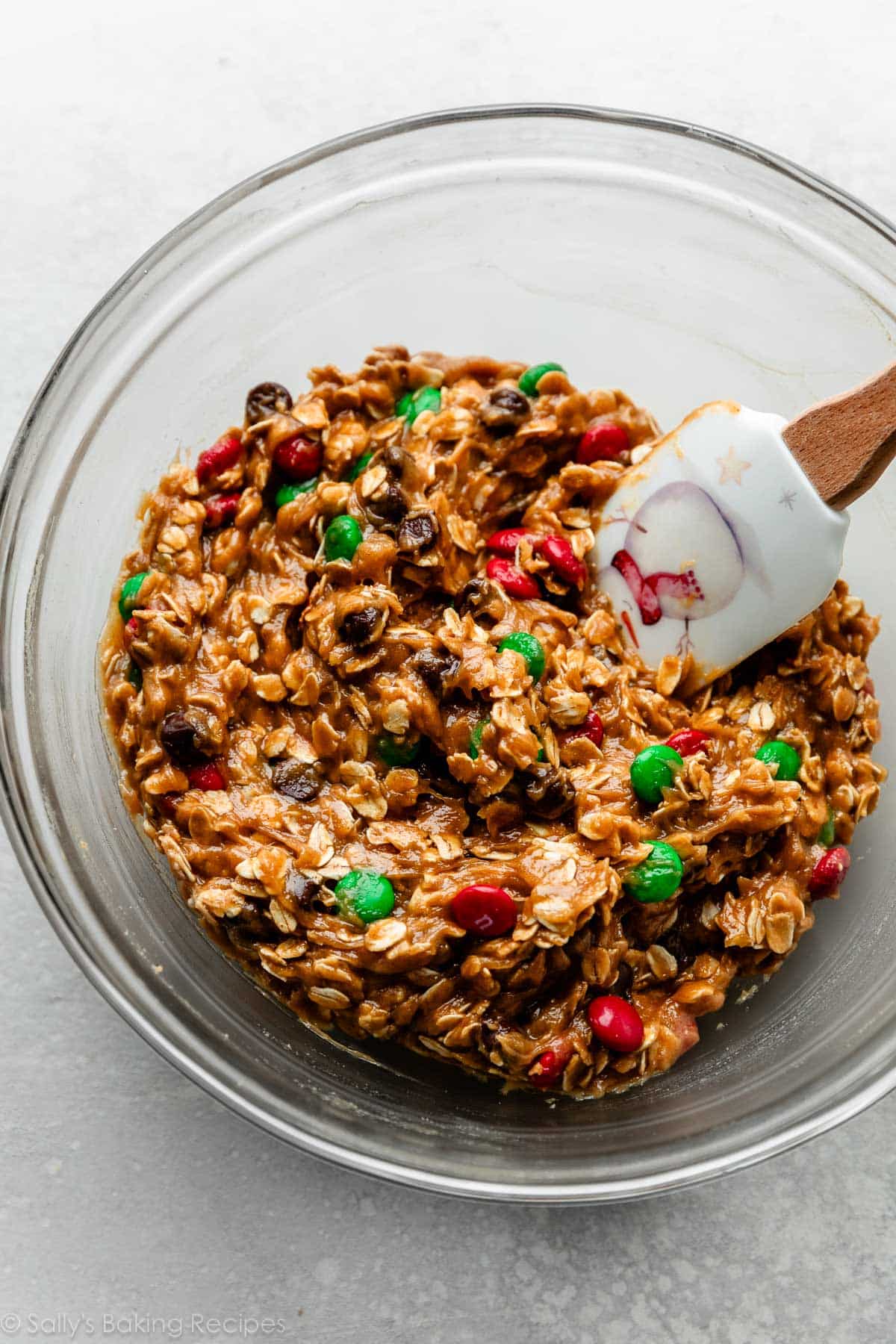 oatmeal peanut butter cookie dough with green and red M&Ms in glass bowl.