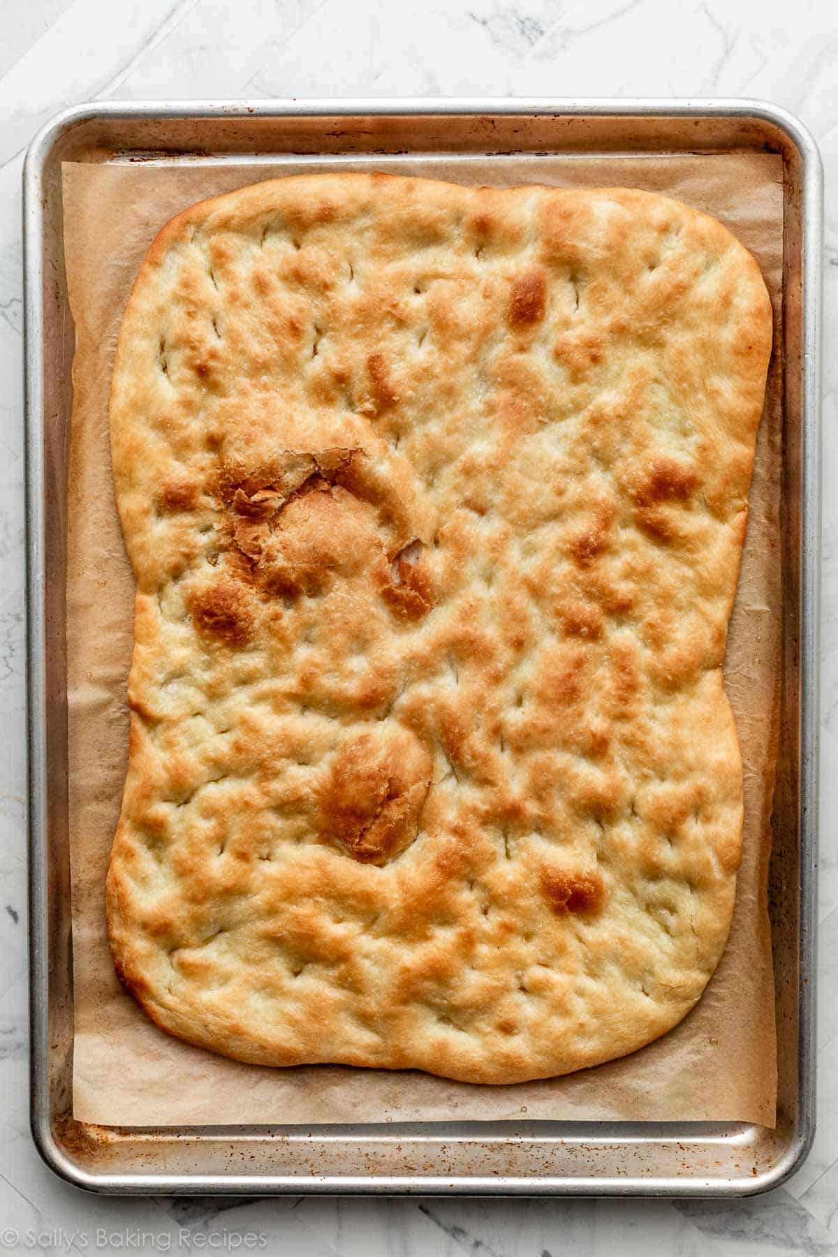baked garlic flatbread dough on lined baking sheet.
