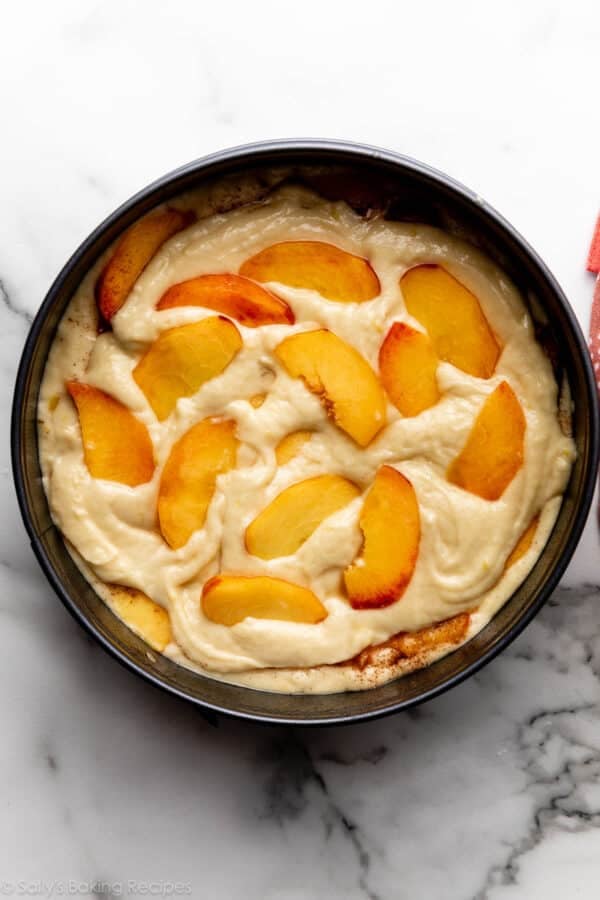 peaches and cake batter layered in pan.