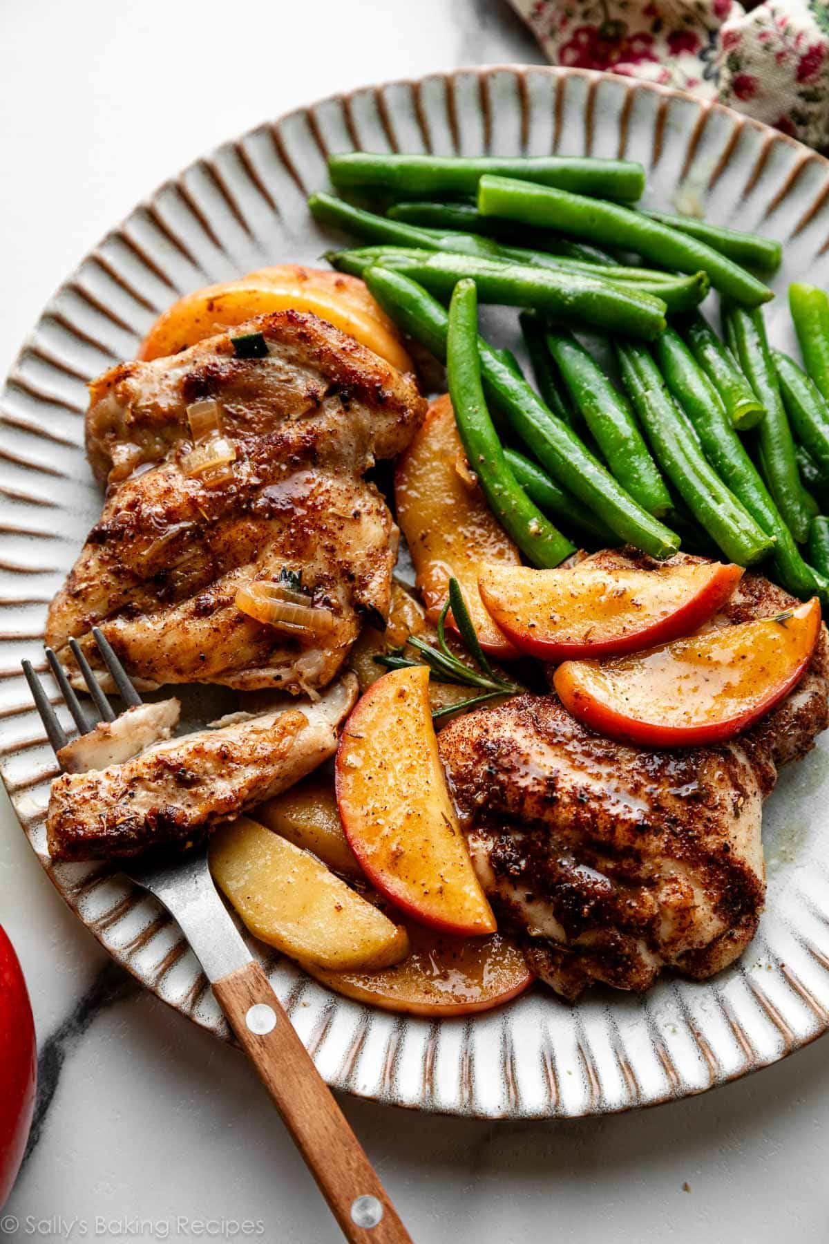 apple cider chicken and apple slices with green beans on plate.
