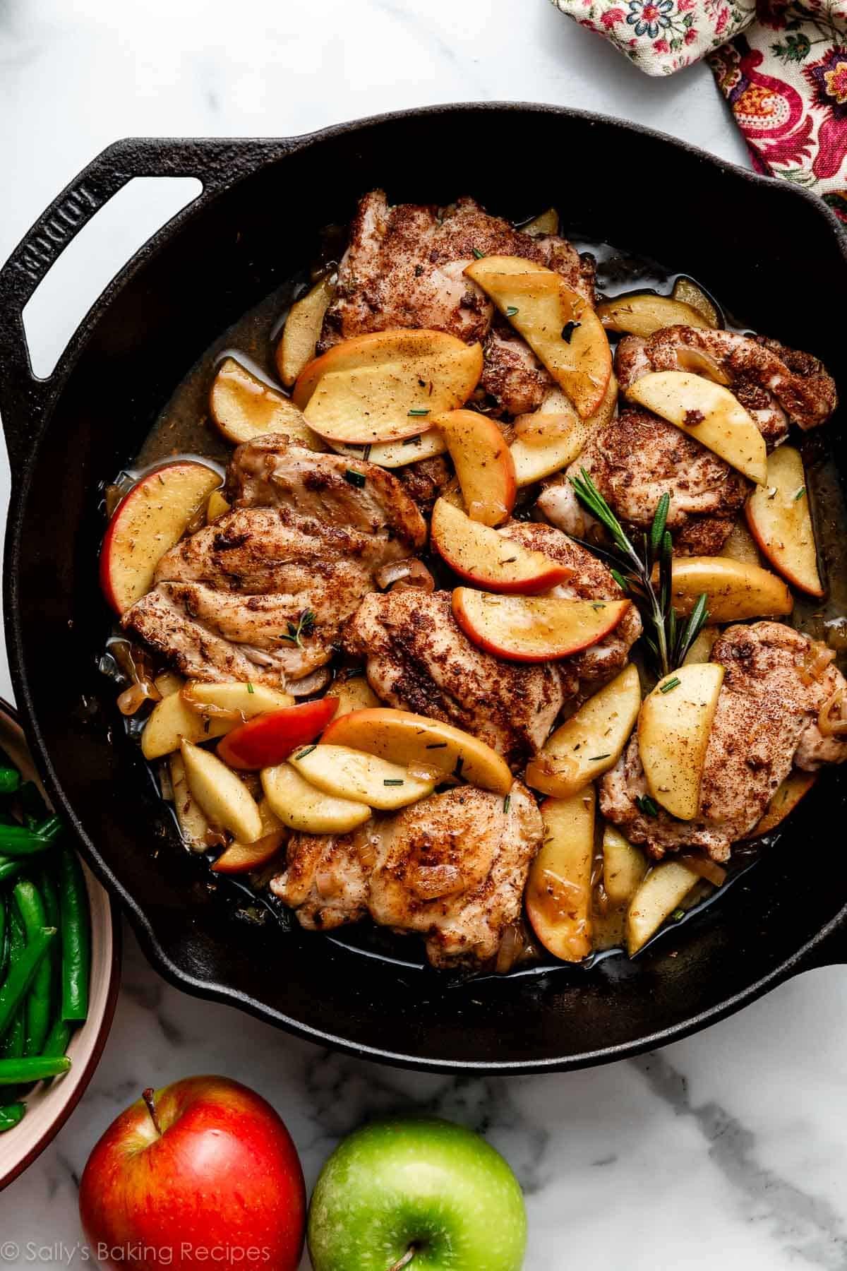 One skillet is all you need to make this flavorful apple cider chicken. Tender chicken thighs are coated with a cozy mix of warm spices, and topped with sweet apples and shallots sautéed in a juicy apple cider pan sauce. An easy dinner recipe you'll want to make on repeat all autumn long! Recipe on sallysbakingaddiction.com