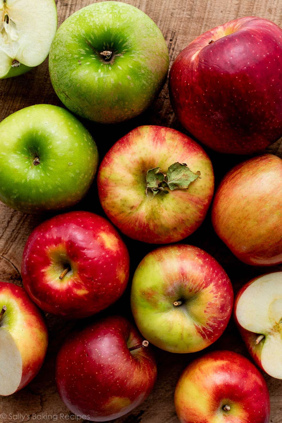 various apple varieties including Honeycrisp, Granny Smith, and Fuji on wood backdrop.