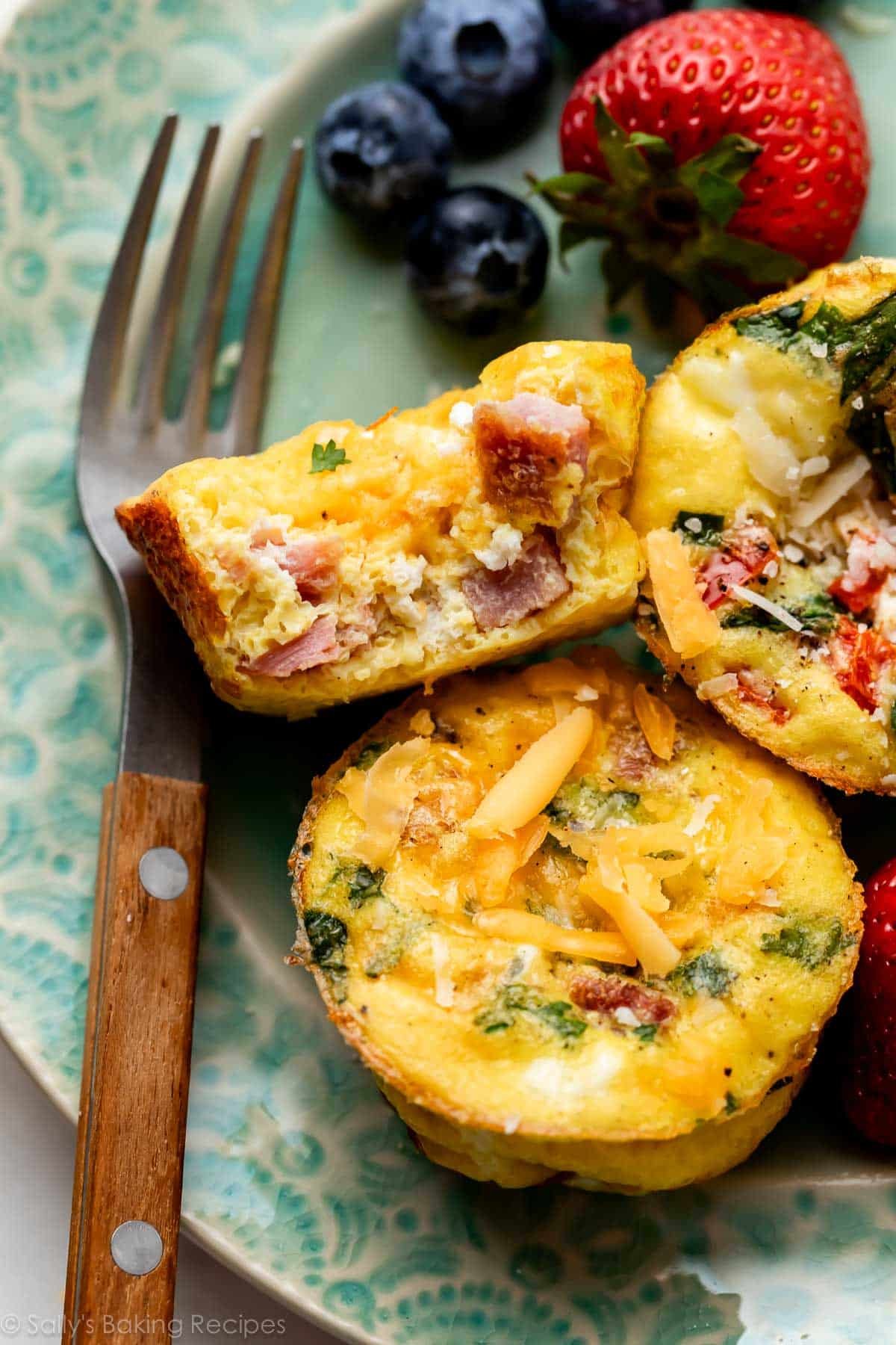 ham and cheese egg muffins on blue plate with berries in background.
