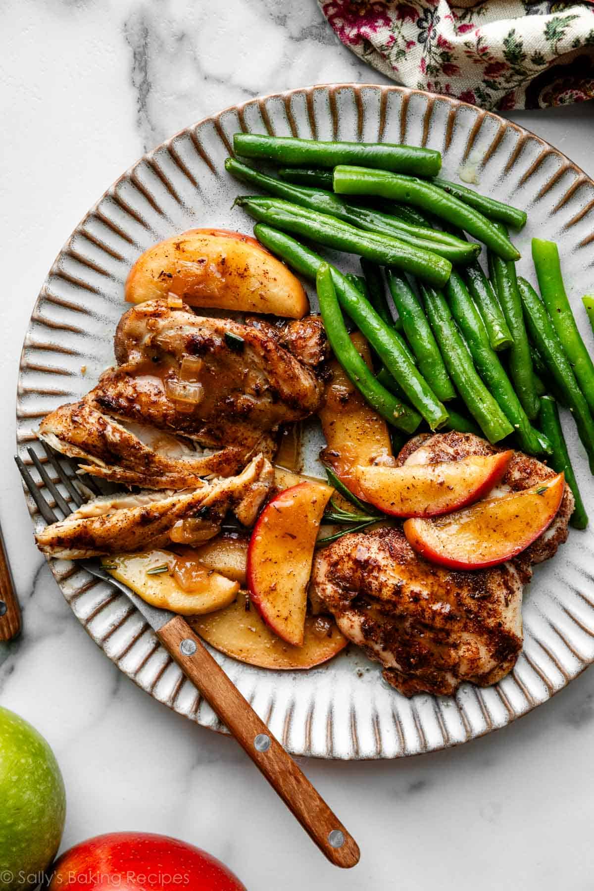 apple cider chicken and apple slices with green beans on plate.