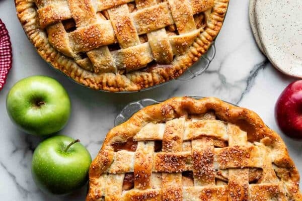 two apple pies shown with lattice pie crust tops and one with a crimped pie crust edge and another with a fluted pie crust edge.