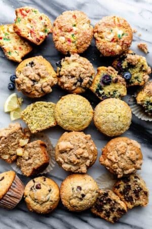 different flavors of muffins lined up on marble backdrop.