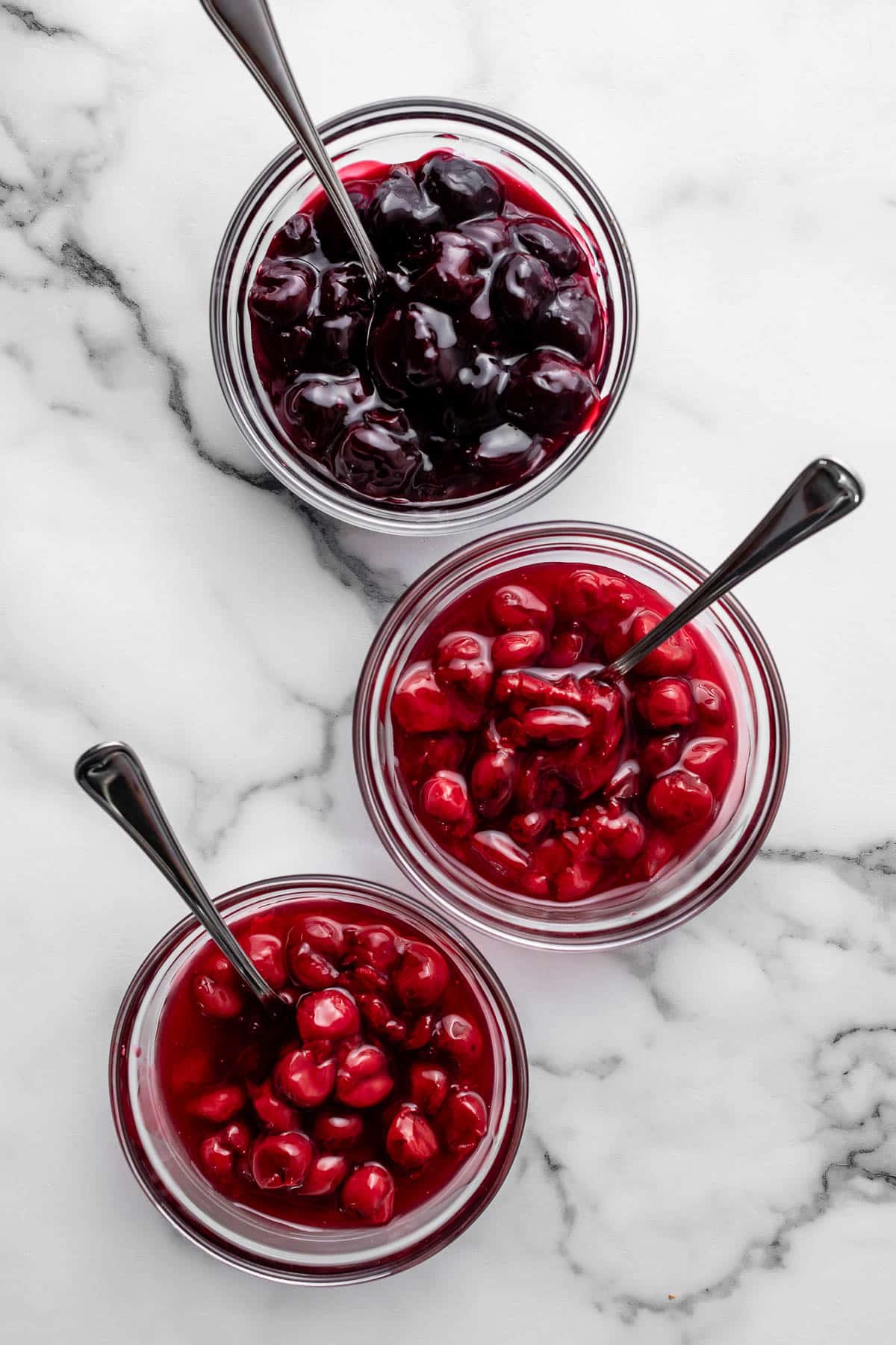 3 bowls of cherry sauce on marble counter.