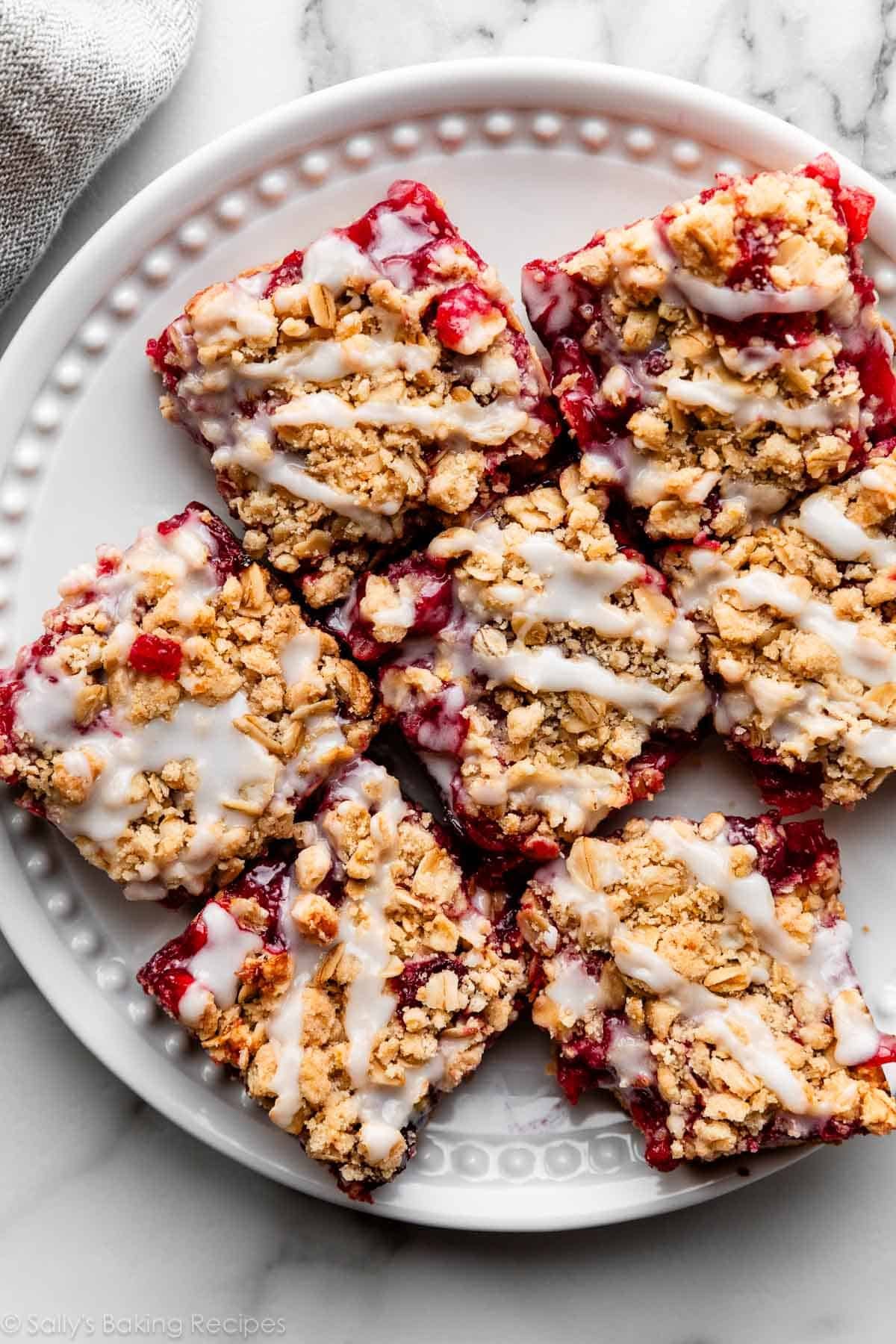 crumb-topped cherry pie bars cut into squares and arranged on white plate.