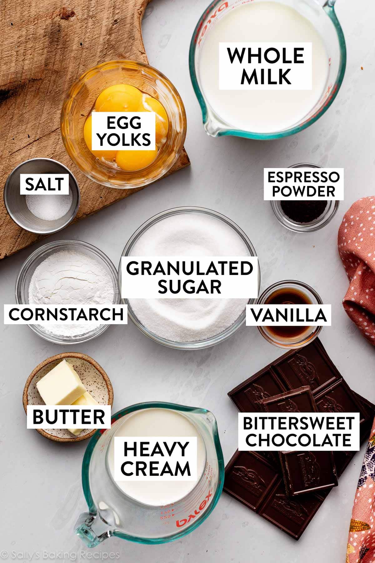 ingredients in bowls on counter including egg yolks, whole milk, chocolate, heavy cream, butter, cornstarch, and sugar.