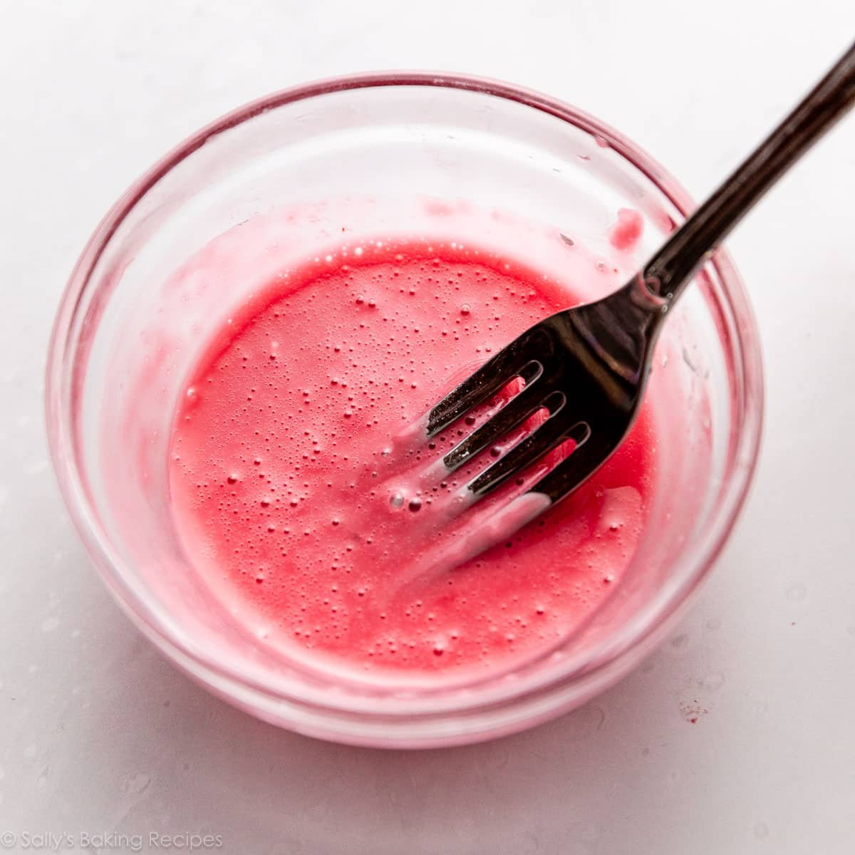fork mixing a pink mixture in a small glass bowl.