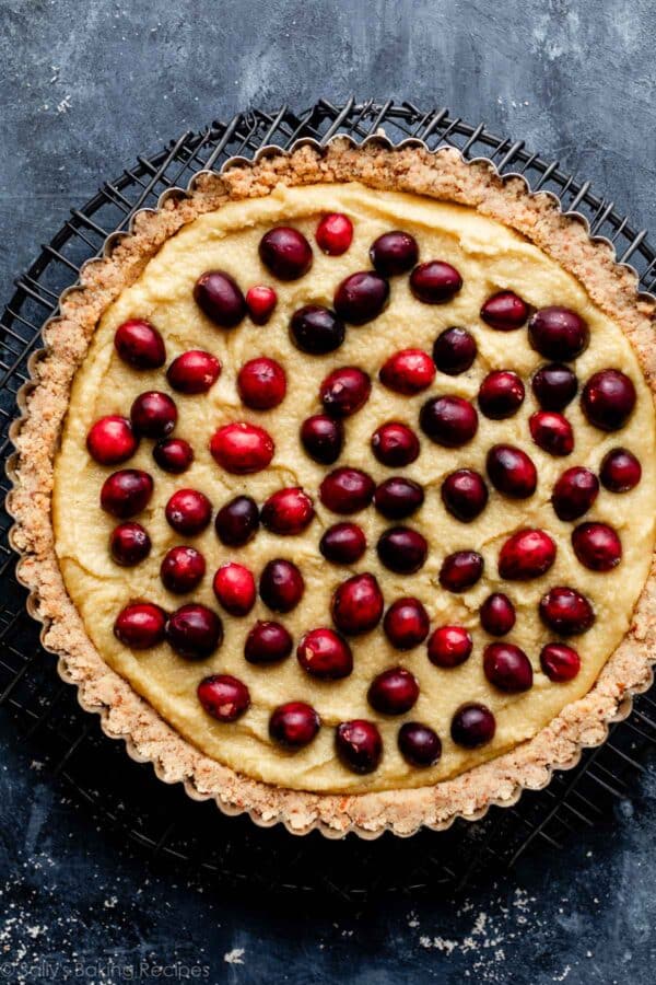 fresh cranberries on top of almond cream in a tart pan.