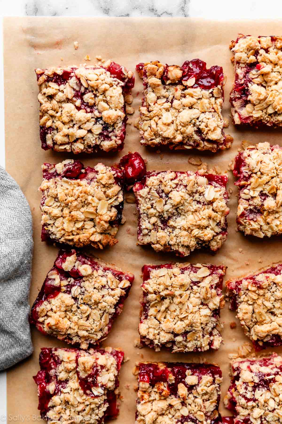 cherry pie bars with crumble topping on brown parchment paper.
