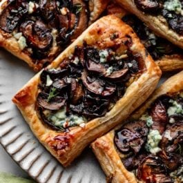 mushroom and gorgonzola cheese puff pastry tarts on silver gray plate.