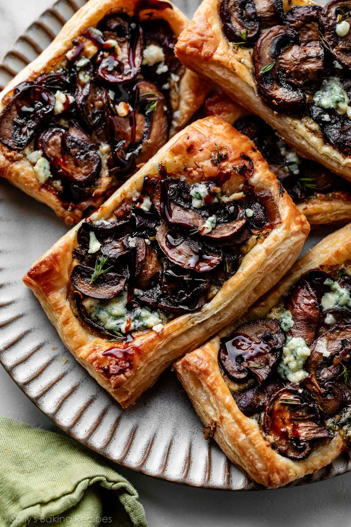 mushroom and gorgonzola cheese puff pastry tarts on silver gray plate.