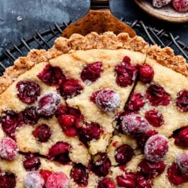 cranberry frangipane tart with slice being removed from the top.