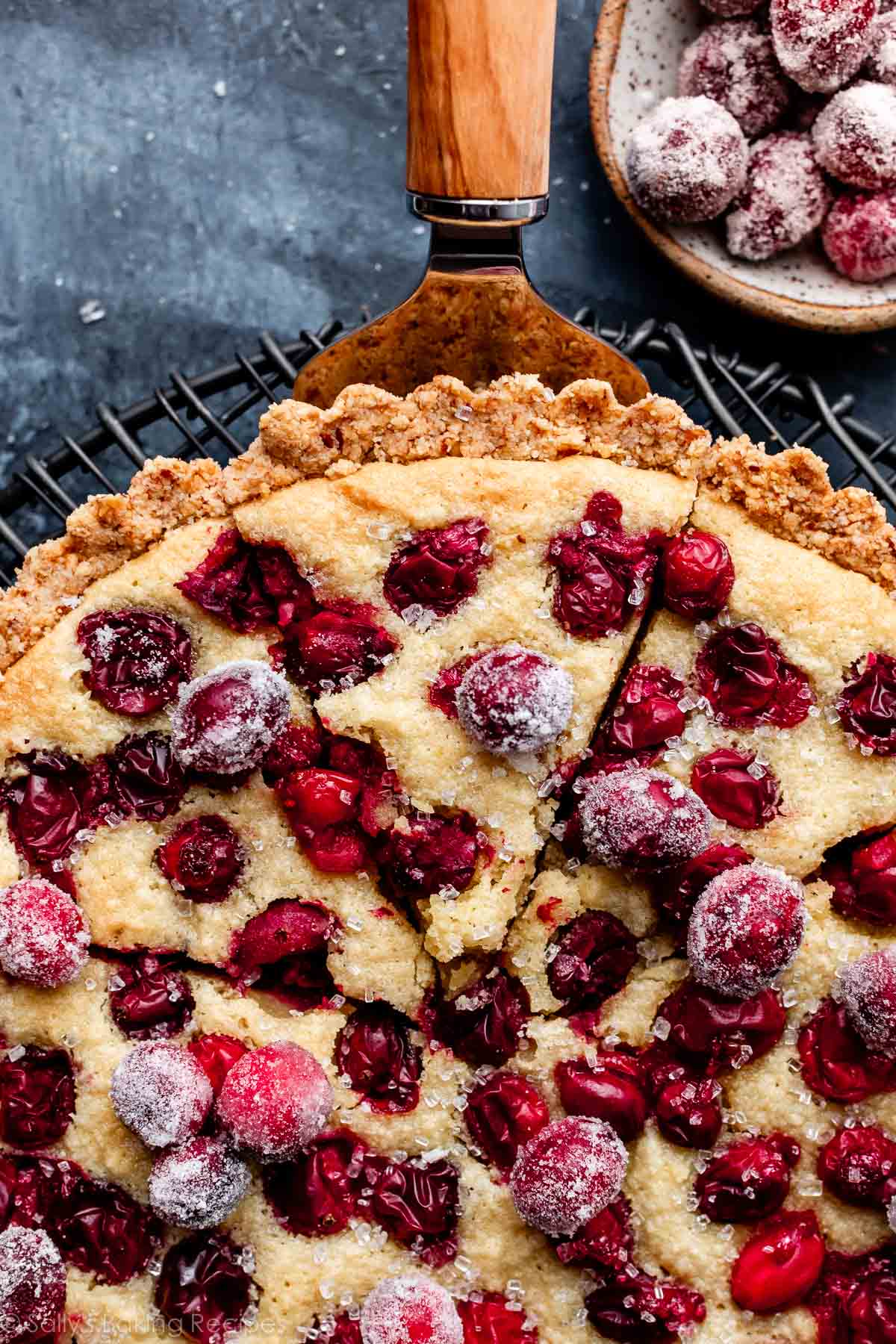 cranberry frangipane tart with slice being removed from the top.