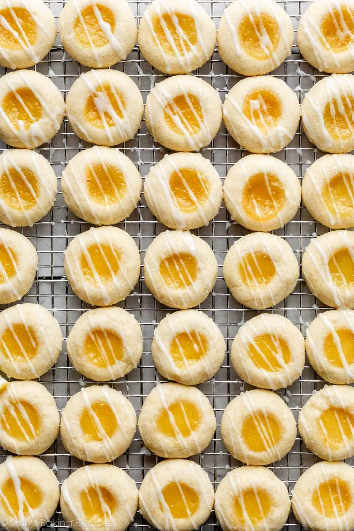lemon curd thumbprint cookies with icing on cooling rack.