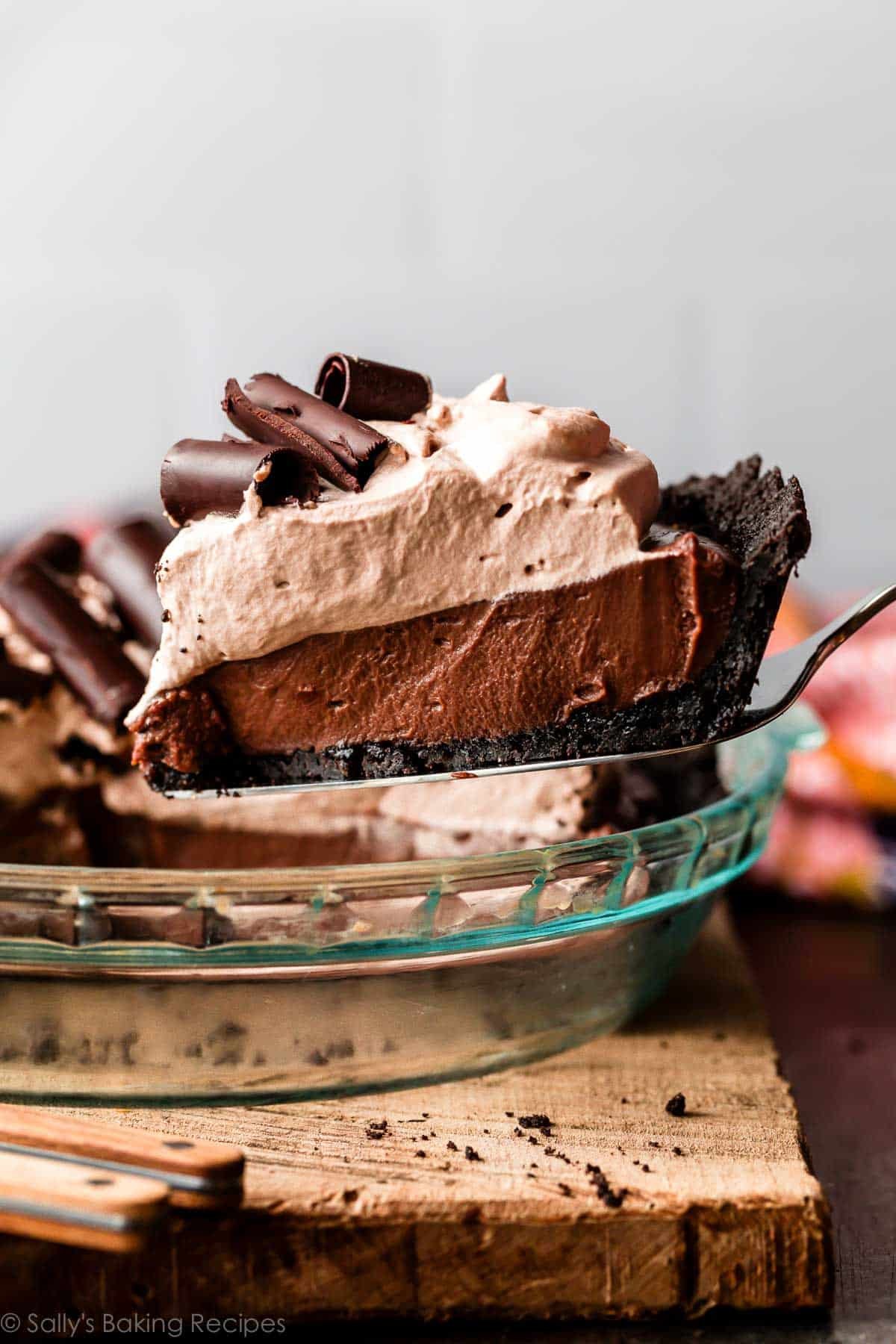 slice of chocolate pudding pie with mocha whipped cream and chocolate curls on top.