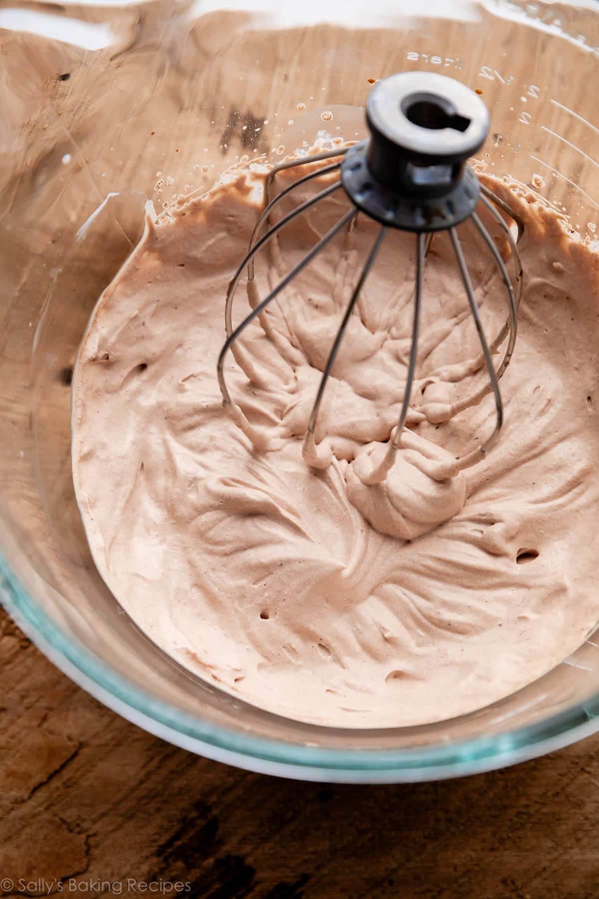 mocha whipped cream with whisk attachment in glass bowl.