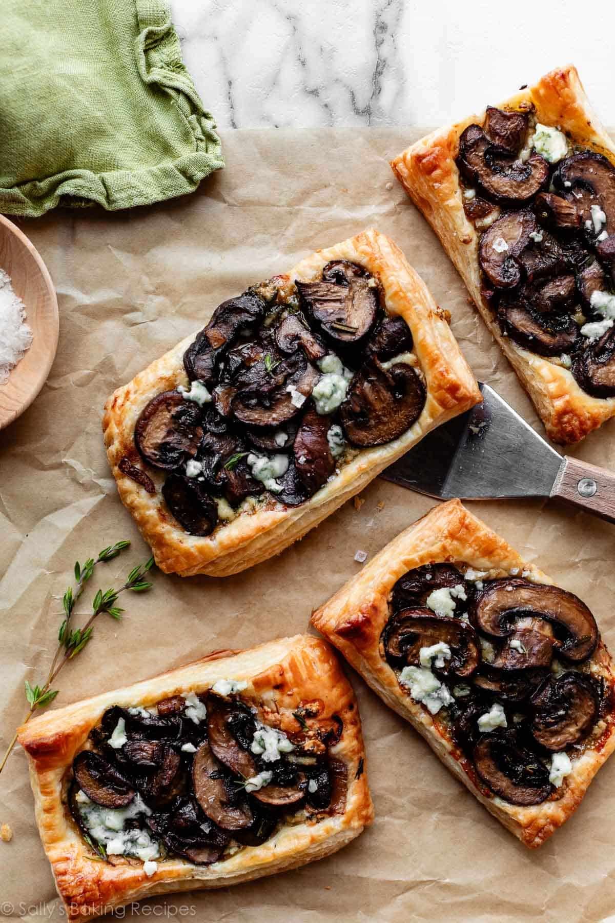 mushroom & gorgonzola cheese puff pastry tarts with fresh thyme on brown parchment paper.