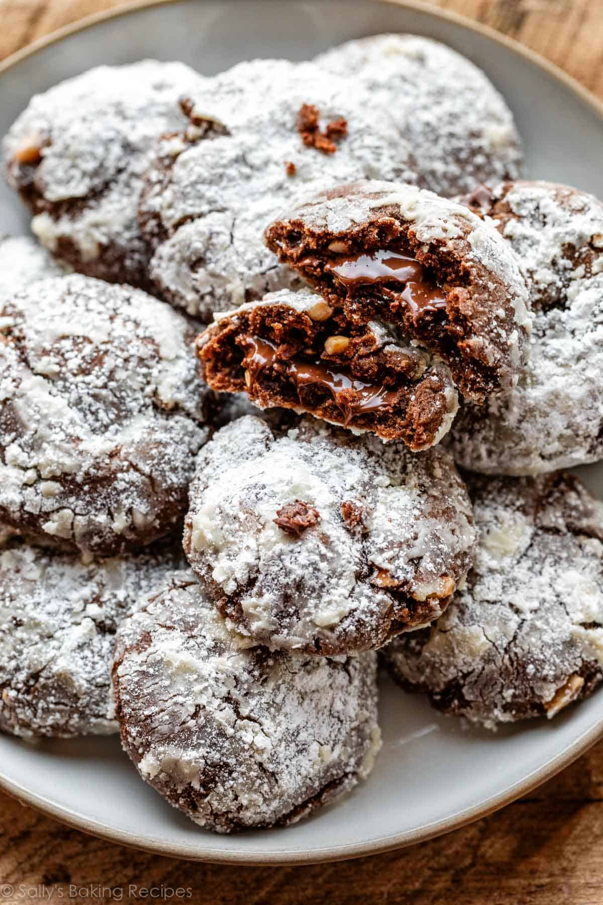 Nutella crinkles on white plate with 1 cookie broken in half to show Nutella in the center.