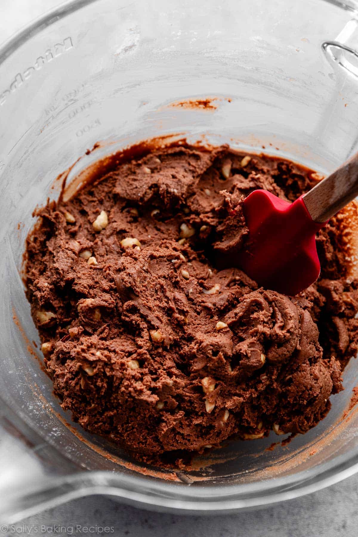 Nutella cookie dough in glass mixing bowl with red spatula.