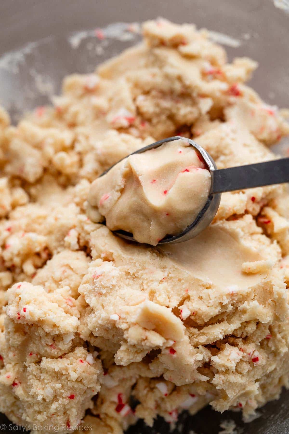 peppermint candy cane cookie dough with Tablespoon scooping out dough.