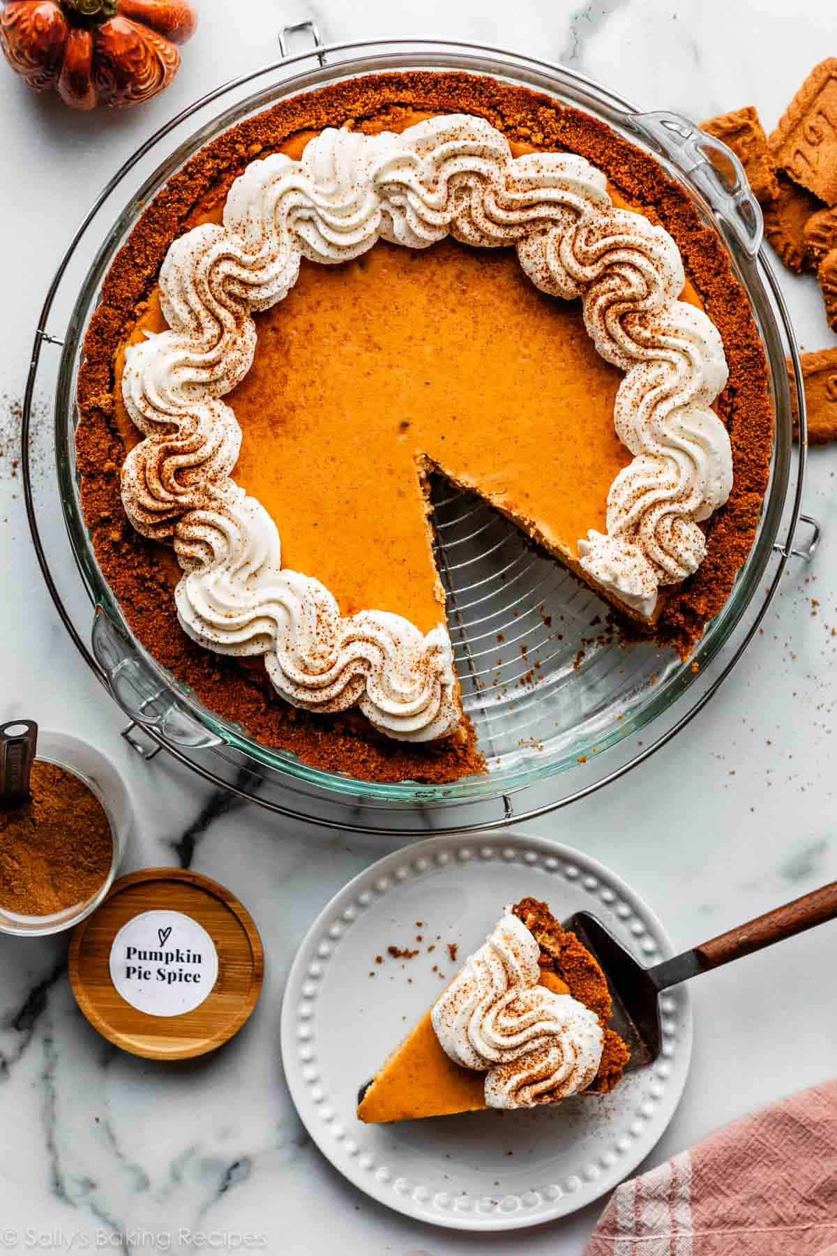 pumpkin cheesecake pie with whipped cream around the border and 1 slice removed and shown on plate.