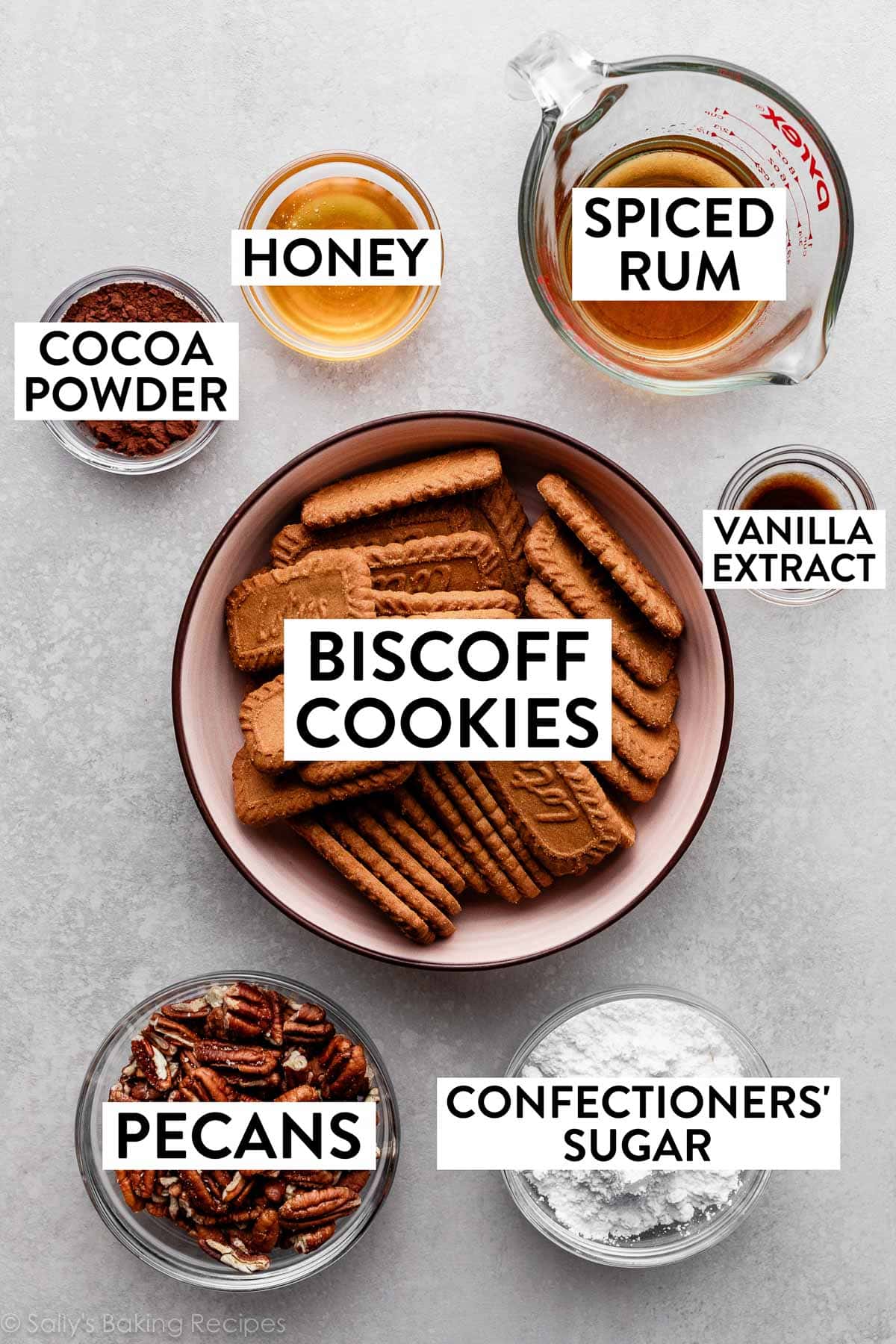 bowls of measured ingredients including Biscoff biscuit cookies, spiced rum, pecans, confectioners' sugar, and cocoa powder.