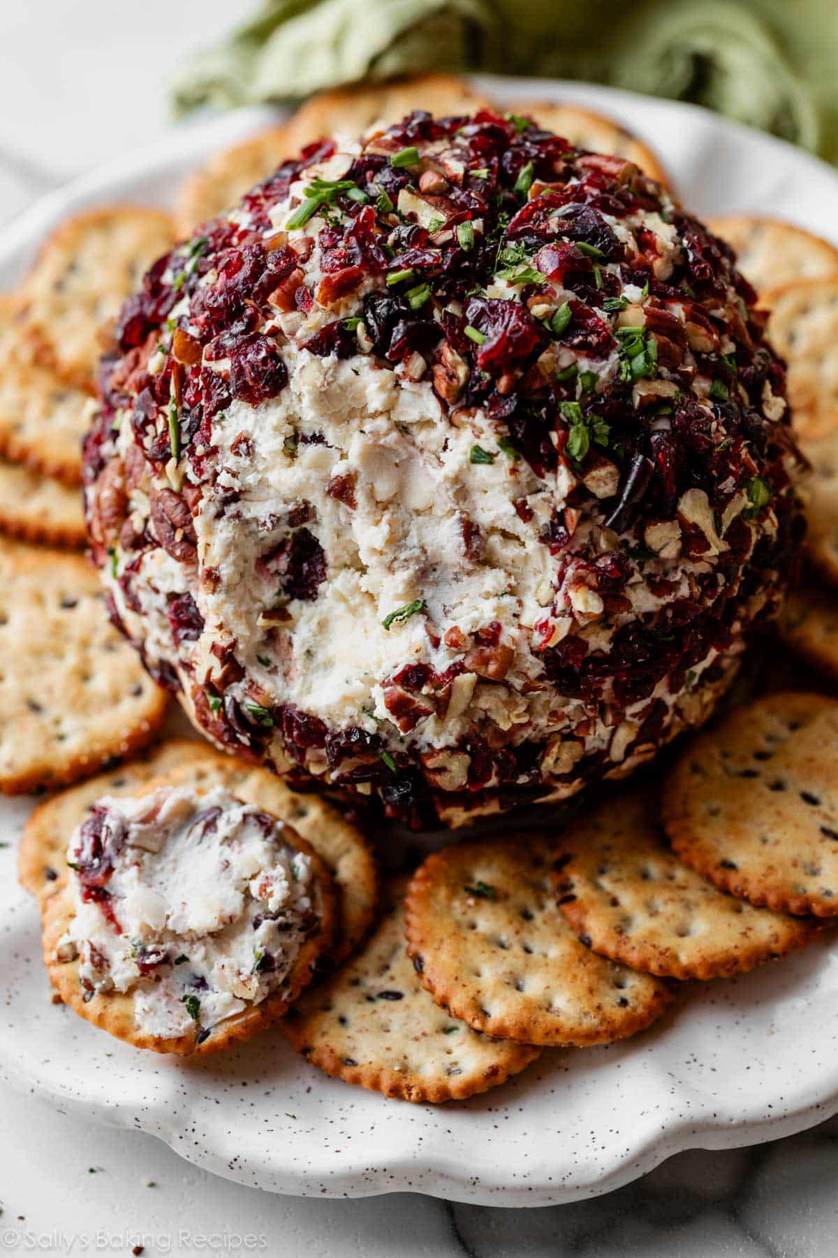 cranberry pecan cheese ball appetizer on plate with crackers.