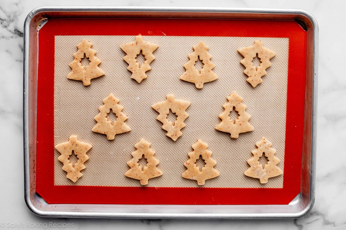 tree-shaped cookie dough with cut-out stars in center on lined baking sheet.