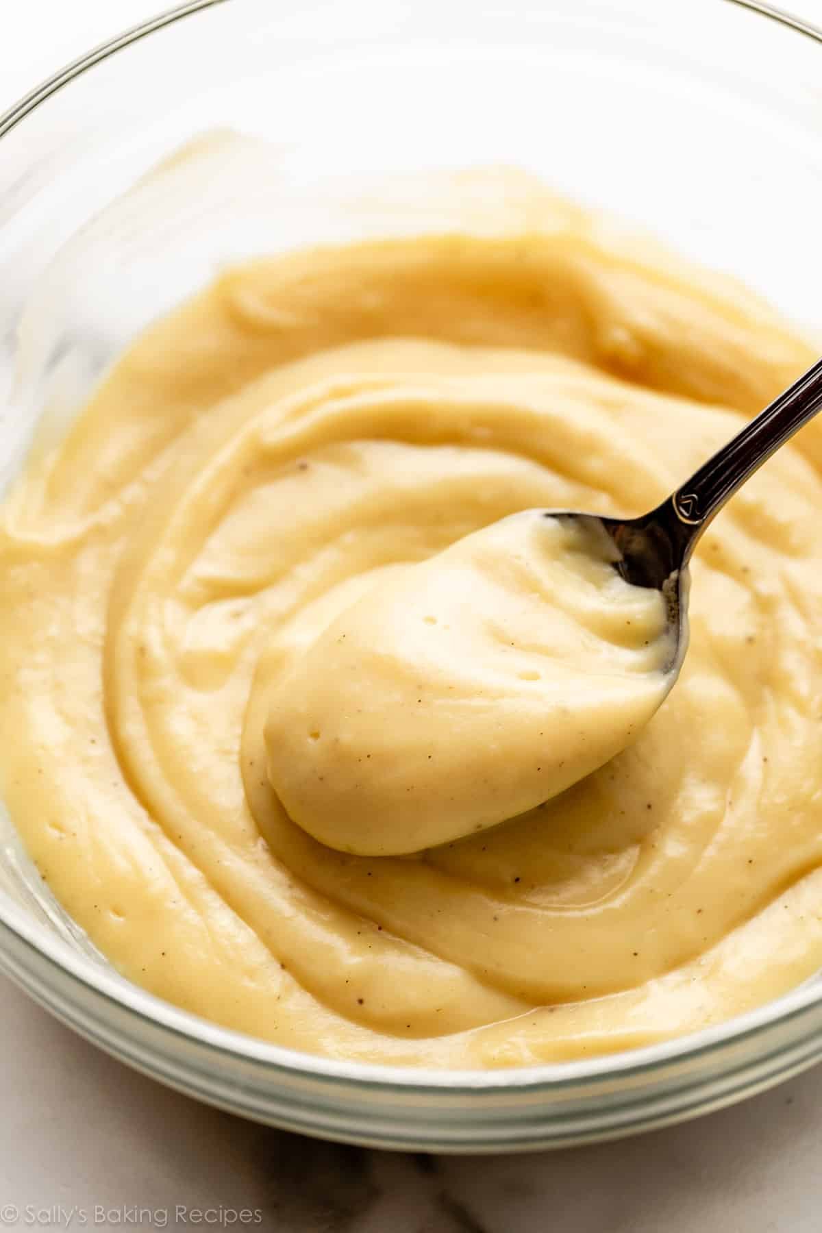 spoonful of creamy pastry cream in glass bowl.