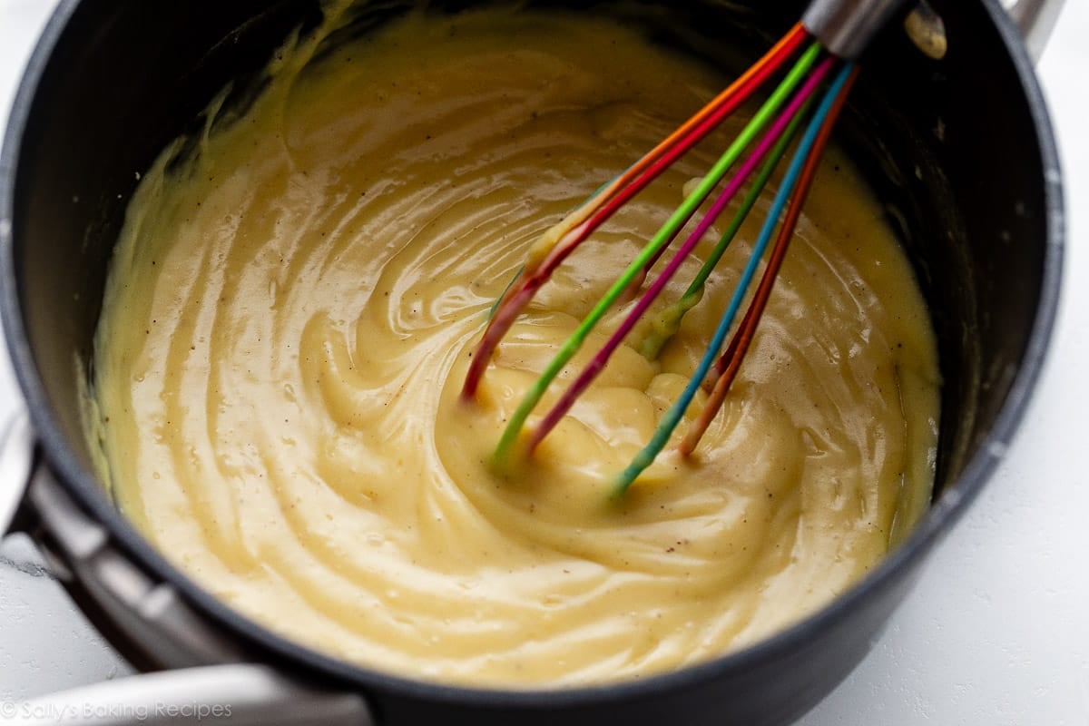 vanilla pastry cream (crème pâtissière) with rainbow whisk in pot.