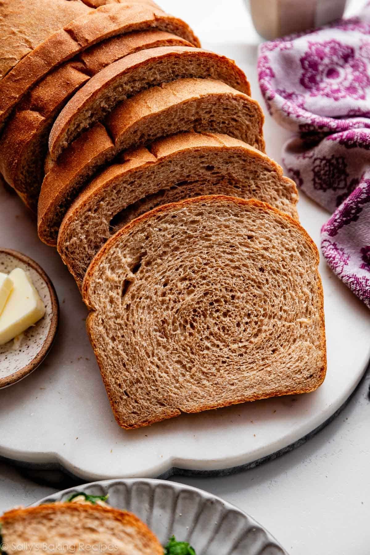 slices of whole wheat bread on marble surface with purple linen on the side.