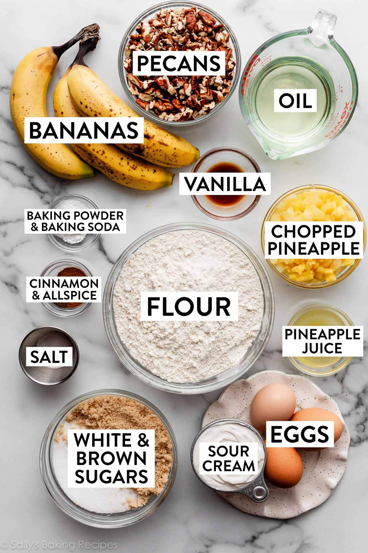 ingredients on counter including pineapple, banana, oil, pecans, vanilla, eggs, sour cream, and sugars.