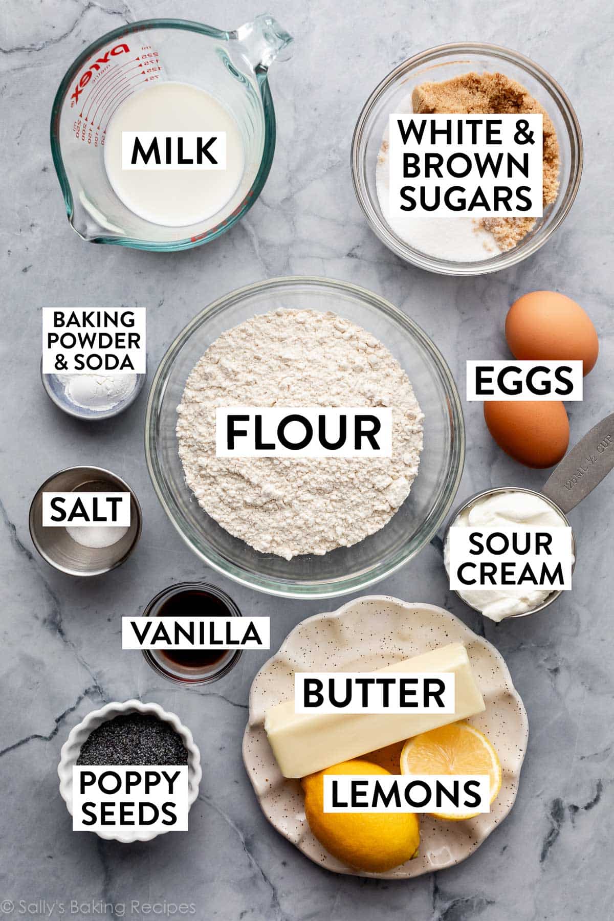 ingredients on marble counter including eggs, butter, flour, sour cream, milk, and sugars.