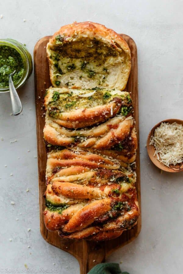 overhead view of a loaf of pesto pull apart-bread on a wood cutting board.