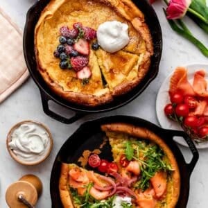 two dutch baby pancakes pictured in cast iron skillets, with one with berries and whipped cream and the other with smoked salmon and arugula.