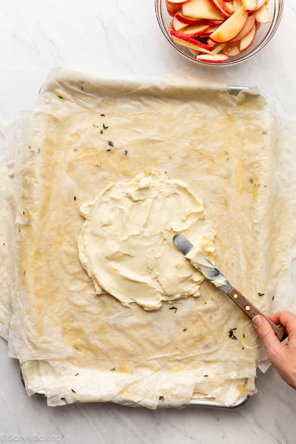 spreading brie cheese on crust dough.