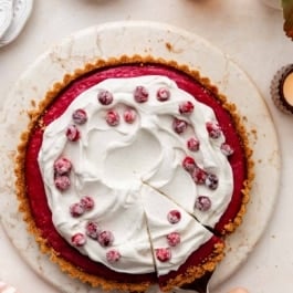cranberry curd tart with whipped cream and sugared cranberries.