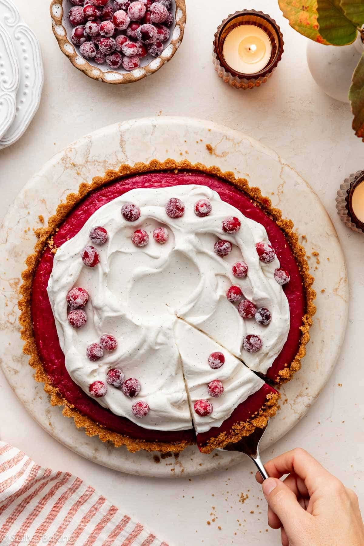 cranberry curd tart with whipped cream and sugared cranberries.