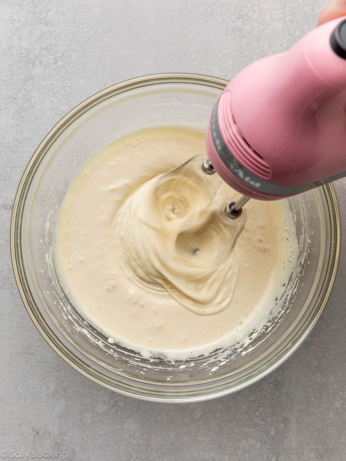 hand mixer beating eggs and sugar in glass bowl.