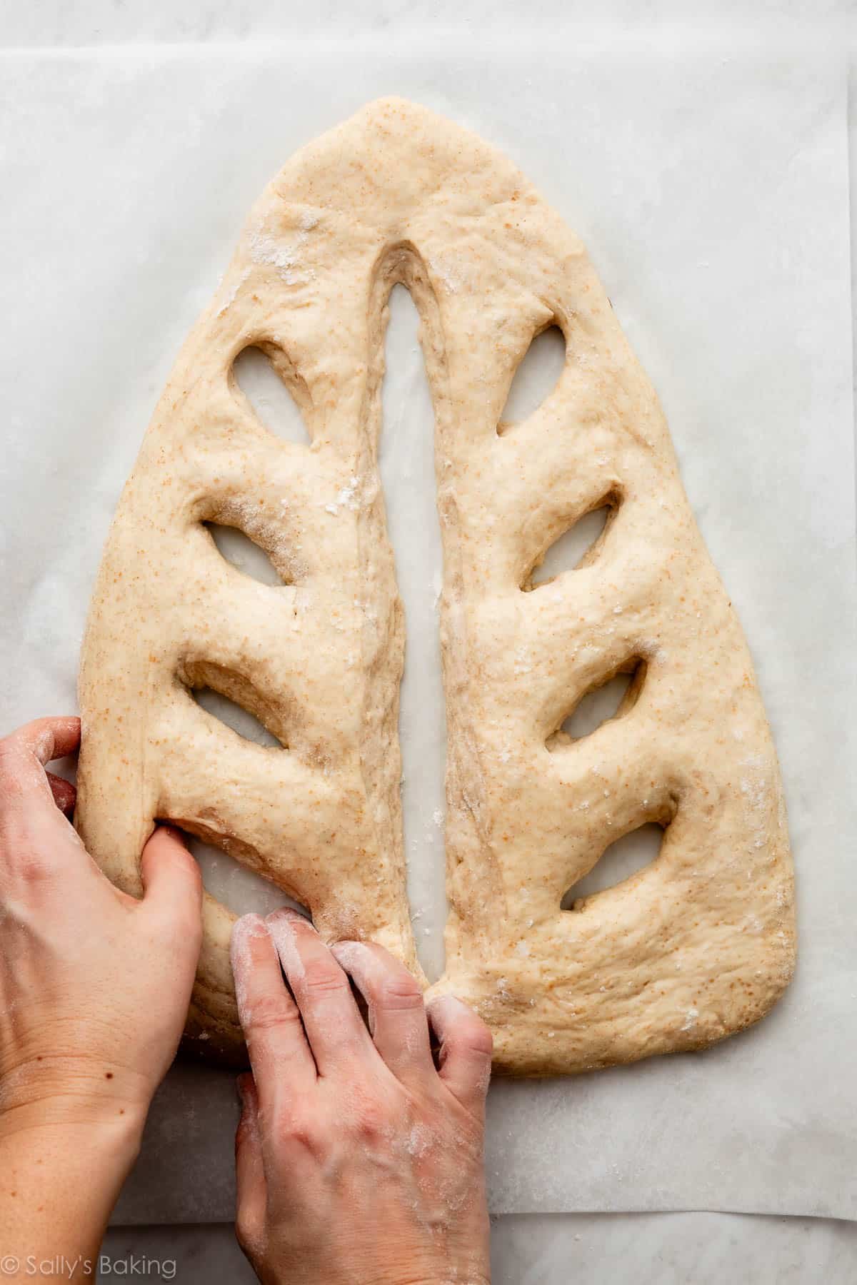 hands shaping fougasse dough.