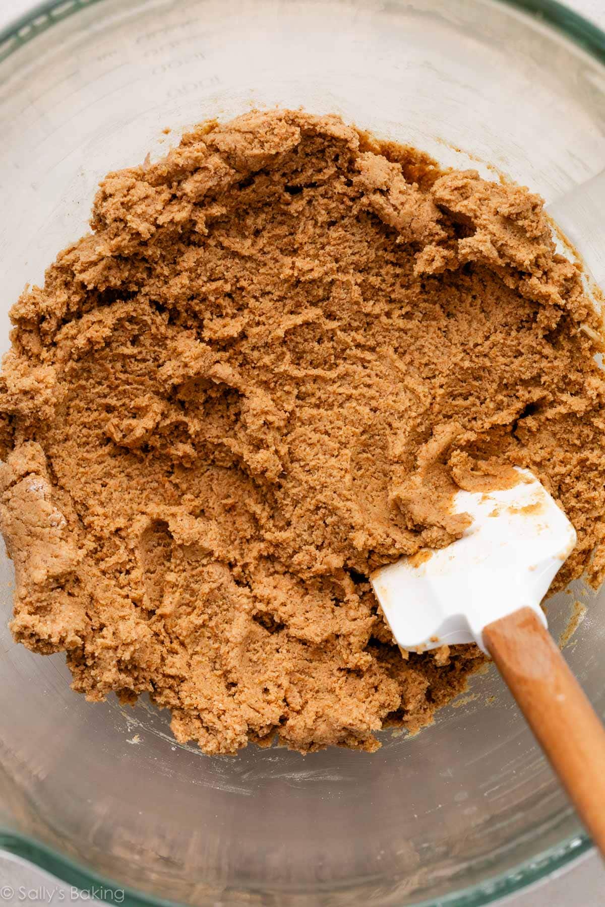 dough in a glass bowl with a spatula.