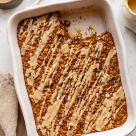 pumpkin baked oatmeal with maple glaze in a white ceramic dish.
