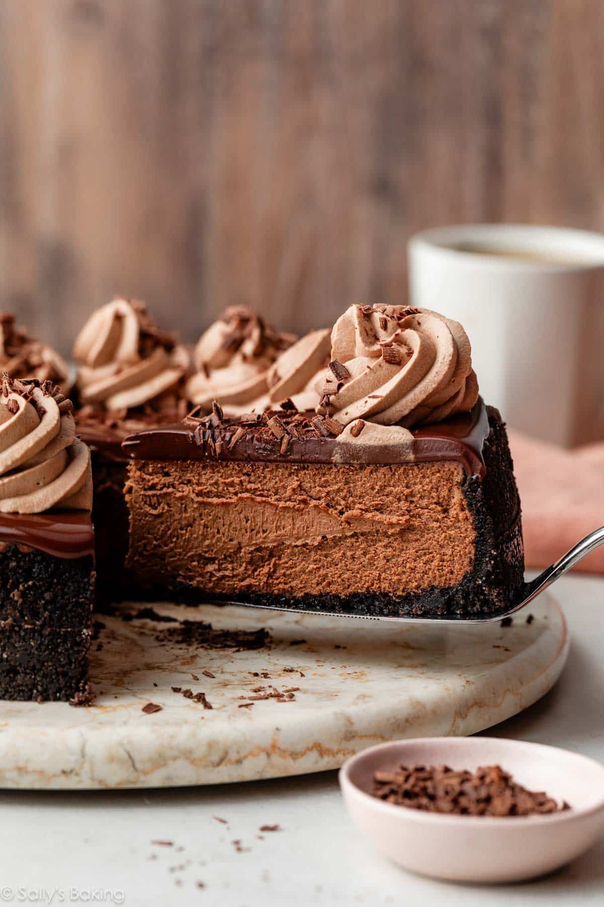 chocolate cheesecake with a slice being removed on a cake server.